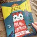Image shows a copy of 'Lukey the Lighthouse finds his Light' book on a sandy beach.