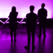 Silhouette of three performers with pink purple light