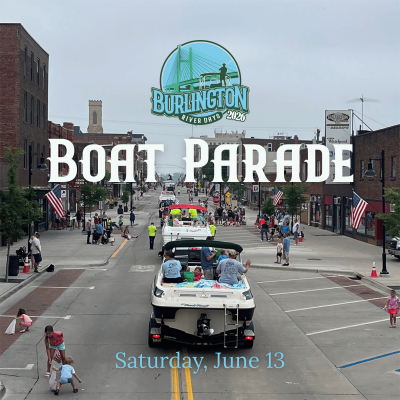 A photo of boats being pulled down a street in a boat parade.