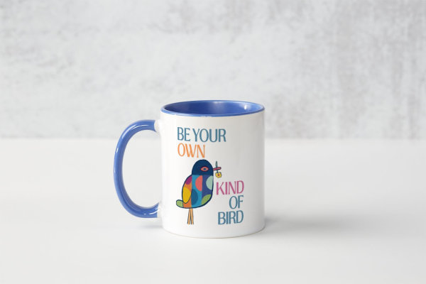 A cermaic white mug with a dark blue inside colour. Our 'Be Your Own Kind of Bird' design shows a multi-coloured bird holding a flower in it's beak.