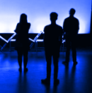 Silhouette of three performers with pink purple light