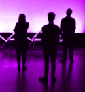 Silhouette of three performers with pink purple light