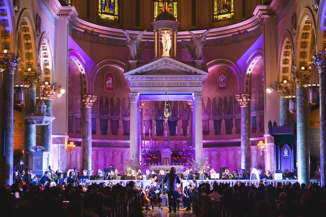 The Fort Greene Orchestra at the altar of Saint Joseph Co-Cathedral, the apse lit violet, a full house below