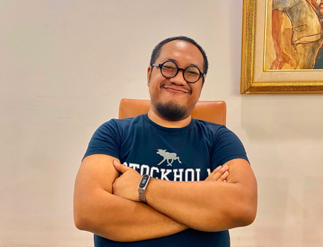 A smiing photo of a man wearing glasses and a blue t-shirt, Tada, the RBC Jakarta host