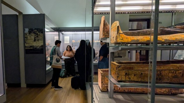 Group of people in a museum with bottom end of sacrophagus on the right hand side.