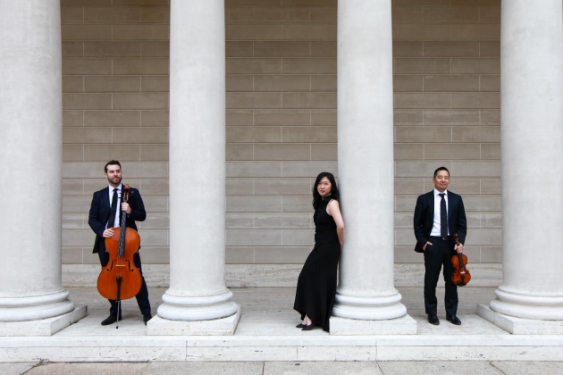 Three musicians standing by tall white columns
