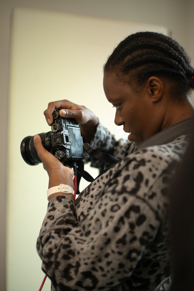 A Black woman holding a camera and looking at the camera screen