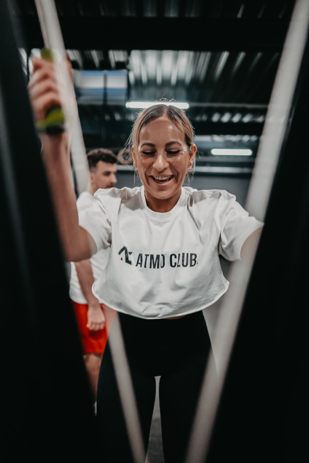 Lächelnde Teilnehmerin beim Training am SkiErg im ATMO CLUB.