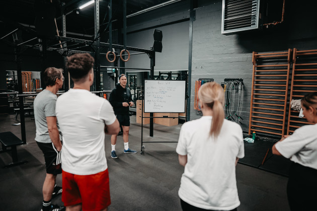 Eine Trainingsgruppe hört einem Coach vor dem Whiteboard im ATMO CLUB zu.