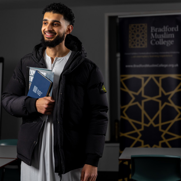 A BMC student holding course books and a college notebook