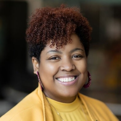 Sherita is smiling while wearing a yellow top.